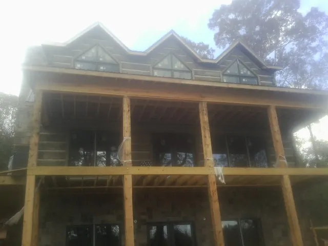 Dormers and porch framing on a large log home under construction — Roof Coating work by our crew in Hayward